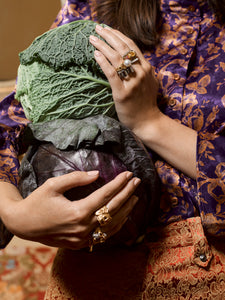 Model holding a cabbage wearing various Elizabeth Allardyce  rings